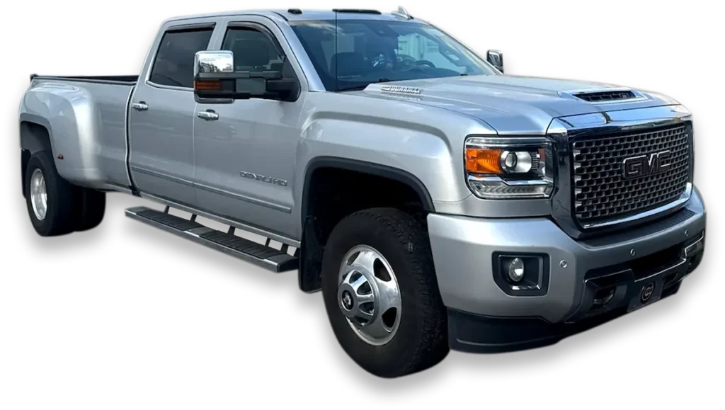 A silver GMC Sierra 3500HD Denali pickup truck, possibly a model from 2017 or 2018, is shown at an angle against a transparent background. The truck is a dually, featuring dual rear wheels, and has a crew cab. The Denali trim is indicated by the grille and other features.
